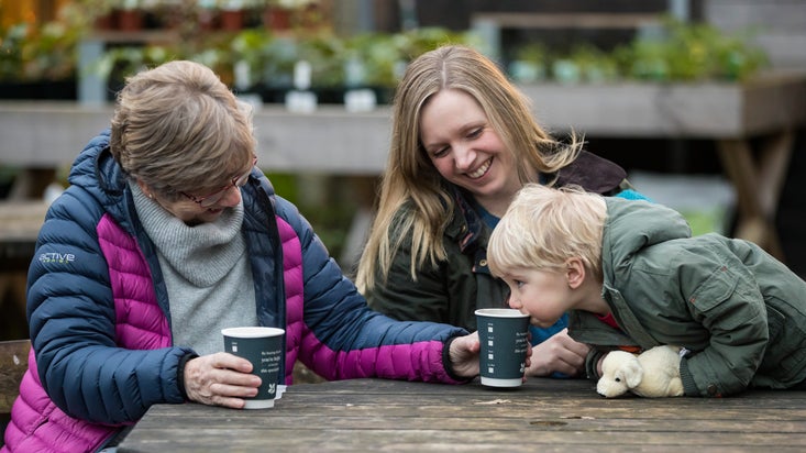 Visitors enjoying a warm drink outside the cafe at Stourhead, Wiltshire